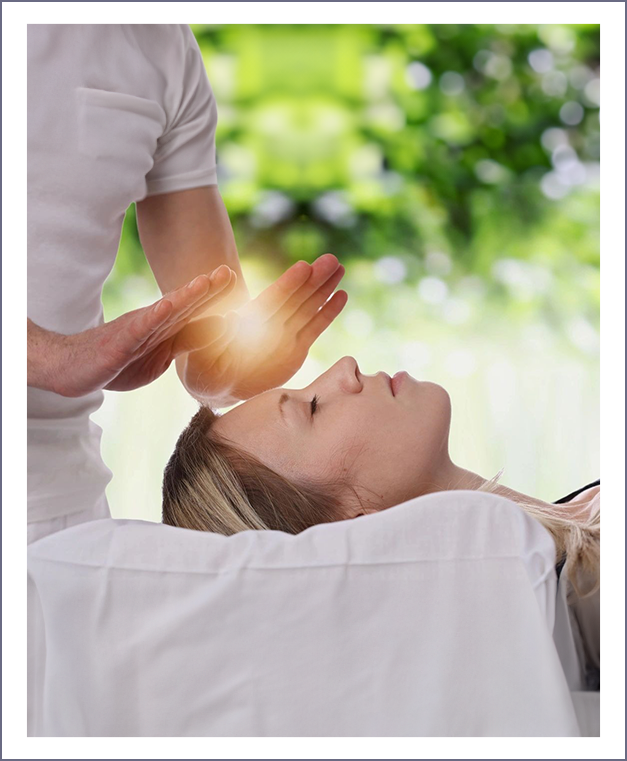 A woman is being given reiki treatment by an energy healer.